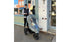 A woman pushing a jogging stroller with a rain cover.