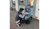 A woman kneeling beside a child in a jogging stroller. The stroller is covered by a weather shield.