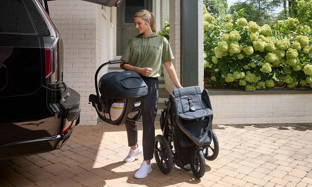 Mother holding the infant car seat and the stroller folded at the same time
